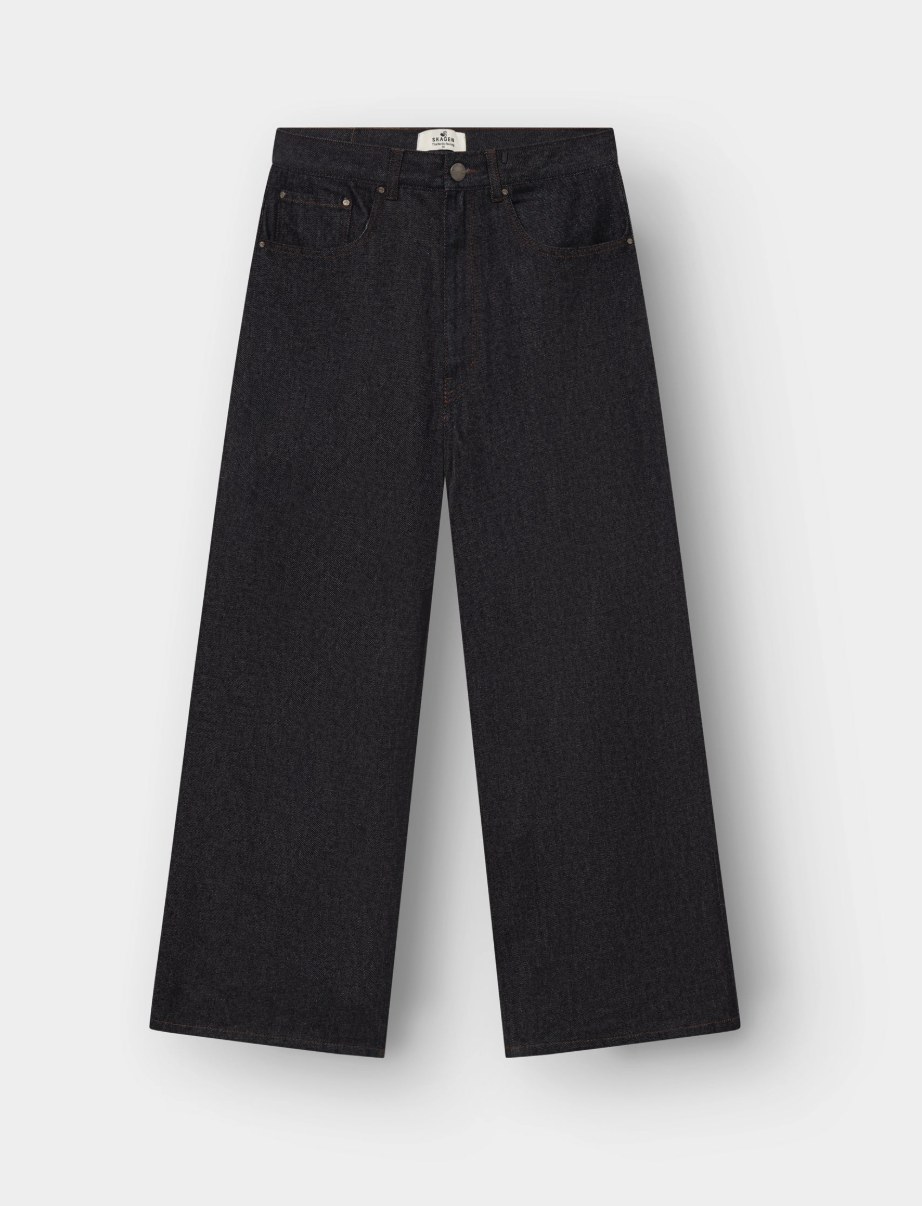 Folded Salvage Supply Company medium wash jeans with bold cream V-shaped embroidered back pocket, branded label, and antique brass button hardware